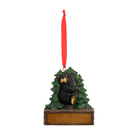 An ornament of a black bear hugging the trunk of an evergreen tree, hanging from a red ribbon. There is a spot in front for customization.