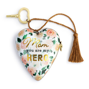 A heart shaped musical sculpture in a pink rose floral pattern that reads "Mom you are my Hero". The heart has a bronze tassel and gold key attached.