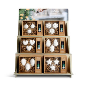 A three tier table top wood displayer with an assortment of boxed mini diffusers in holiday themes.