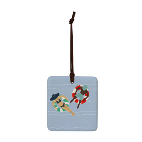 A square blue hanging tile magnet ornament with an illustration of people on floats in the water.