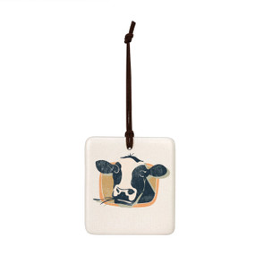 A square white tile hanging magnet ornament with a black and white cow on a tan background.