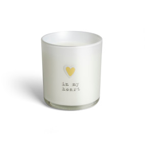 A white glass candle that says "in my heart" and has a small white and yellow heart on the front.