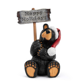 A grand figurine of a sitting black bear wearing a Santa hat and holding a sign that says "Happy Holidays". The sign is reversible and removable.