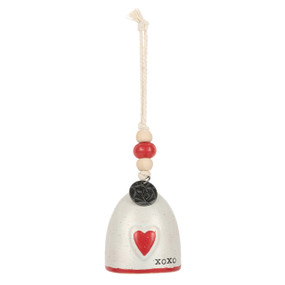 A mini white bell with a red heart and "XOXO" on the front. There are beads and a metal token at the top of the bell.