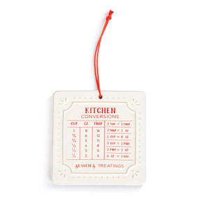 A square white ceramic magnet with common kitchen conversions written in red. It has a red hanger.
