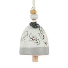 A mini white and gray bell with an image of Christopher Robin reattaching Eeyore's tail. There are beads and a metal token at the top of the bell.