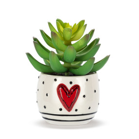 A mini white ceramic container with black dots, stripes and a raised red heart on the front. The container has an artificial succulent.