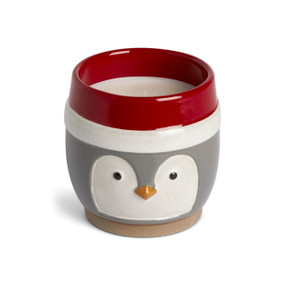 A round ceramic filled candle with the face of a penguin in gray and white with a red rim.