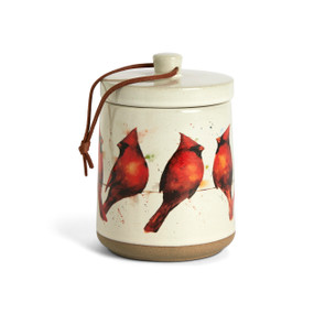 A cream ceramic candle with watercolor cardinals around the outside and a removable lid.