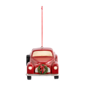 A red truck ornament with a green wreath on the front grill.