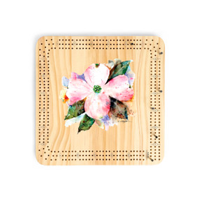 A light wood cribbage board game with the watercolor image of a blooming American dogwood in the middle.