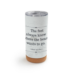 A white cork bottom tumbler with a clear plastic lid. The tumbler says "The feet always know where the heart wants to go" with the hundred acre wood lightly in the background.