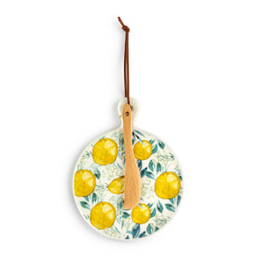 A round ceramic mini serving board with illustrated yellow lemons. The board has a small wood knife attached.