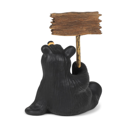 Back view of a sitting black bear figurine holding a sign that says "I'm Not Fat I'm Fluffy!".