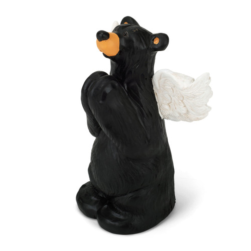 A figurine of a standing black bear with white wings, holding his paws together in prayer, displayed angled to the left.