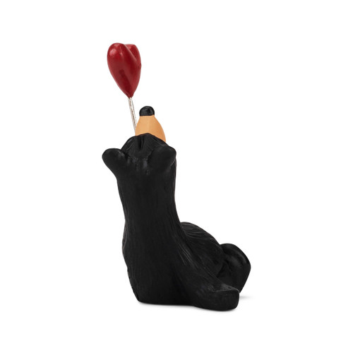 Right profile view of a sitting black bear figurine holding a red heart shaped balloon.