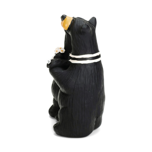 Left profile view of a figurine of a bride and groom black bear with the bride showing off her ring and holding a bouquet of flowers.