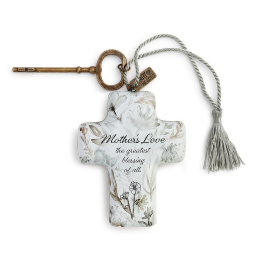 A white floral print art cross with a bronze key and a silver tassel.