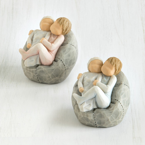 Set of two grey bean bags with two small baby figurines sitting hugging one another on it