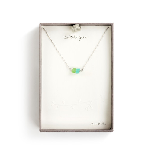 A silver necklace with a blue and green pebble pendant in a gray cardboard box.