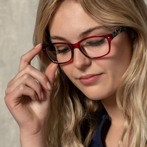 A close up image of a woman in a blue blouse wearing a pair of red animal print glasses.