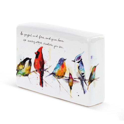A side view of a white ceramic plaque with five watercolor painted birds on a tree branch and be joyful and free, and give love to every other creature you see" in black cursive font."