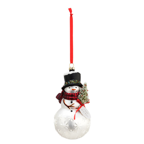 A small blown glass ornament of a snowman, wearing a black top hat and a red scarf, holding a small Christmas tree. With a red ribbon string.