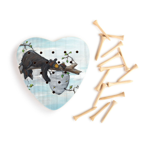 Heart shaped wood peg game with a painted image of a bear on a branch next to a beehive, next to a set of wood pegs.