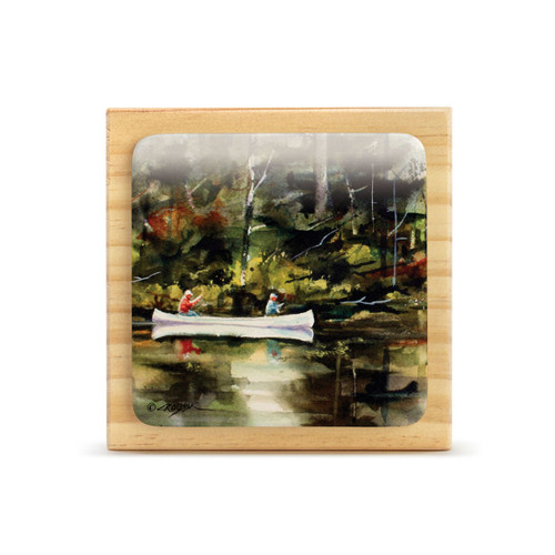 A square wood plaque with a tile attached that has a watercolor image of a canoe on the water.