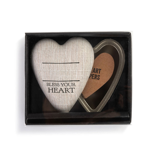 A heart shaped container with a wood grain lid that says "Bless Your Heart" under two black lines, with the lid offset to the base, in a packaging box.