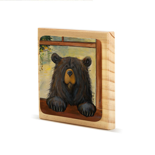 A square wood plaque with an attached painted tile of a black bear peeking through a window, displayed angled to the left.