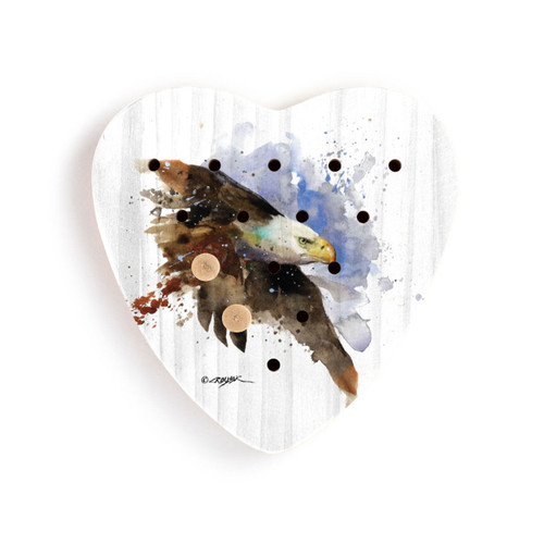A heart shaped wood peg game with a painting of a bald eagle, with two wood pegs in it.
