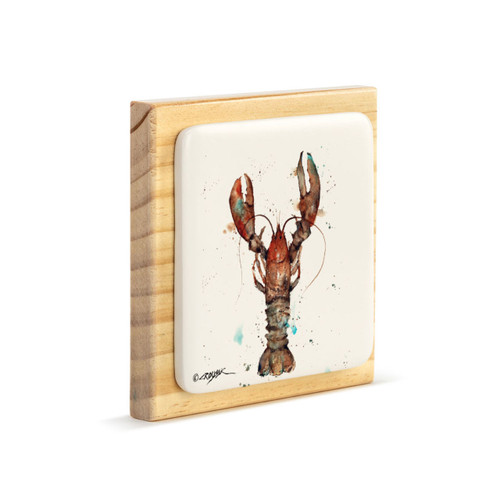 A square wood plaque angled to the right with a tile attached that has a watercolor image of a lobster.
