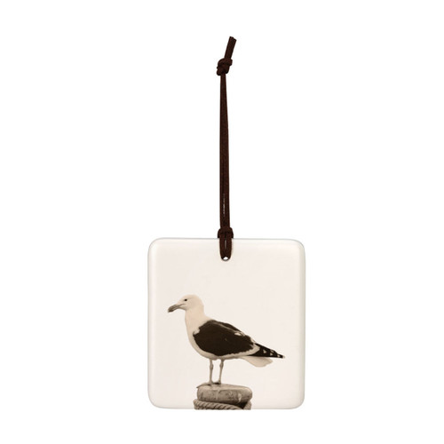 A white square tile hanging ornament with the image of a sea gull.