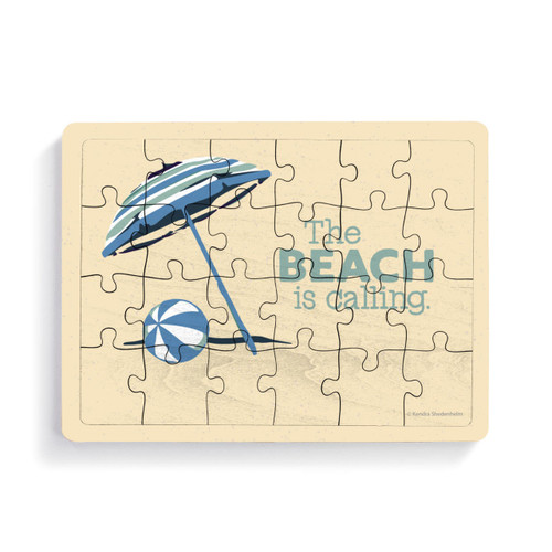A rectangular 24 piece wood puzzle postcard with a beach ball and umbrella with the saying "The Beach is calling."