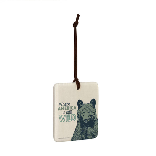 A square hanging ornament with the image of a bear that says "Where America is still Wild" angled to the right.