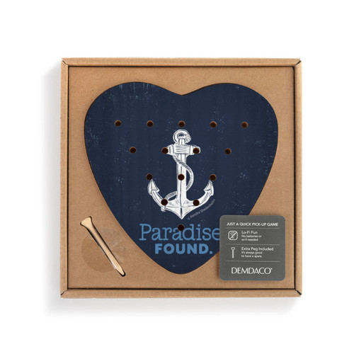 A dark blue heart shaped wood peg game with a white anchor and the saying "Paradise Found" inside a cardboard packaging box with a product information tag.