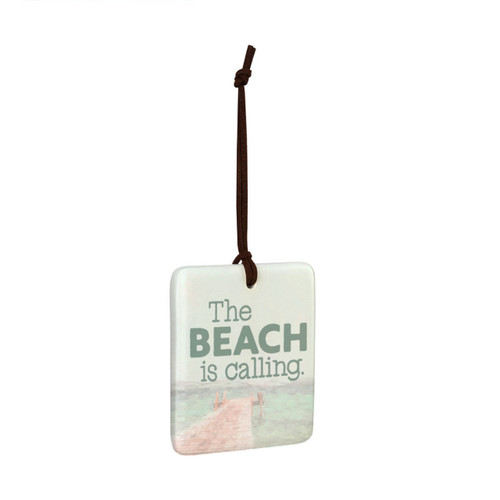 A square tile hanging ornament with a lake pier scene that says "The Beach is Calling", displayed angled to the right.