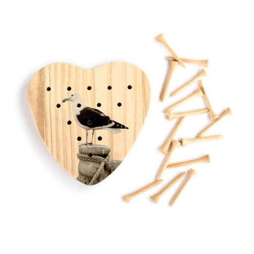 A heart shaped wood peg game that has the image of a sea gull, next to a set of wood pegs.