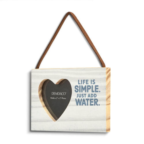 A rectangular wood hanging ornament with a 2 inch heart shaped opening for a photo next to the saying "Life is Simple. Just Add Water." on a light wood background, angled to the left.
