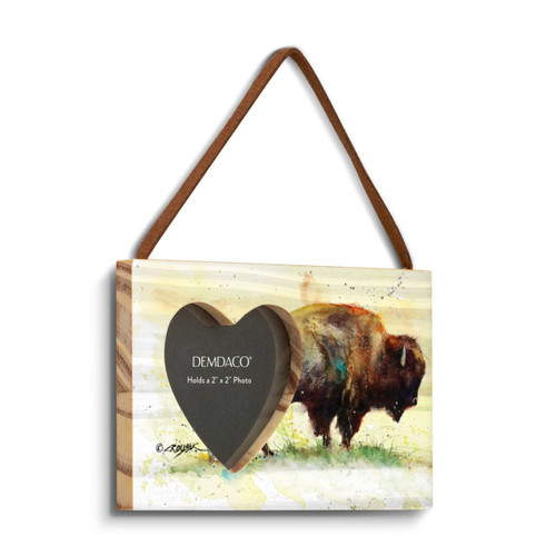 A rectangular wood hanging frame with a heart shaped 2 inch photo opening next to a watercolor image of a standing buffalo, displayed angled to the right.