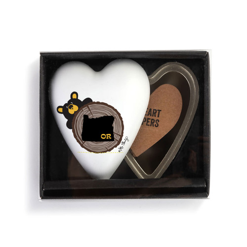 Heart shaped keeper with the image of a black bear peeking over a tree stump with Oregon on it, displayed in a packaging box.