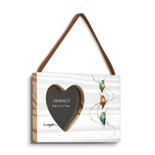 A rectangular wood hanging frame with a heart shaped 2 inch photo opening next to a watercolor image of three hummingbirds, displayed angled to the right.