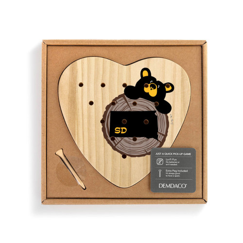 Heart shaped wood peg game with a black bear peeking over a wood stump with South Dakota on it, shown in a packaging box with a product information tag.