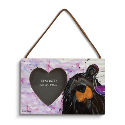 A rectangular wood hanging frame with a 2x2 inch heart shaped photo opening and has a painted image of a black bear holding a glass of wine.