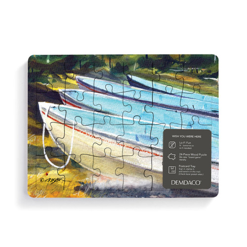 A 24 piece postcard puzzle with a watercolor image of boats on a beach, with a product information tag attached.