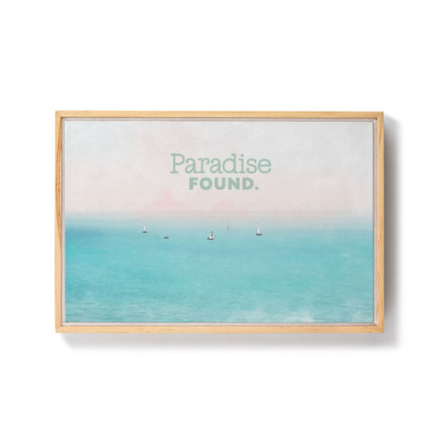 A framed image of water with sailboats in the distance and the saying "Paradise Found."