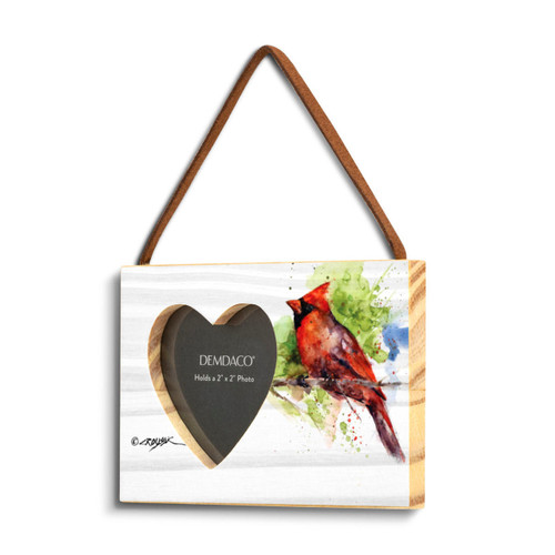 A rectangular wood hanging frame with a heart shaped 2 inch photo opening next to a watercolor image of a cardinal on a branch, displayed angled to the left.