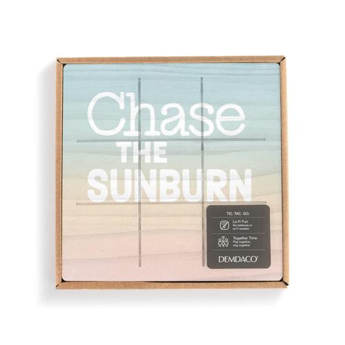 A square wood board for tic tac toe in sunset colors that says "Chase the Sunburn" in a packaging box with a product information tag.