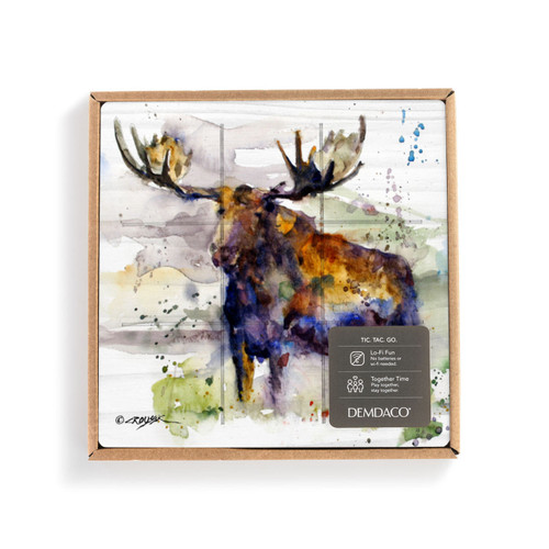 A square wood tic tac toe board with a watercolor image of a standing moose, displayed in a packaging box with a product information tag.